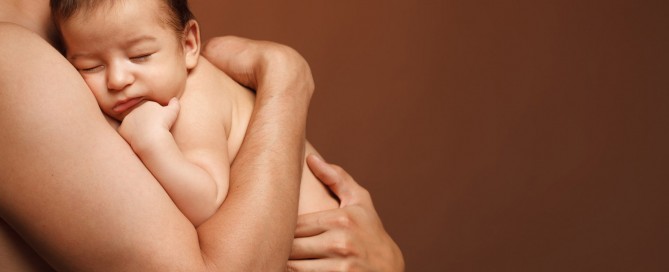 Newborn baby sleeping on the shoulder of his father the over brown background